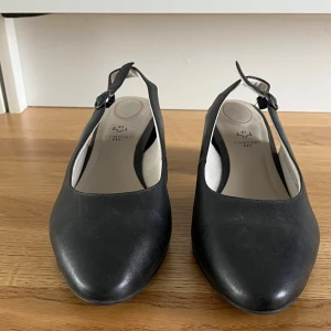 Svarta klackskor  - Säljer dessa svarta klackskor. Stängs via ett spänne bak och har en extra mjuk sula så att man inte får ont i fötterna. Tyvärr är de dock lite för stora för mig så är endast testade en kort stund (utomhus). Högsta höjden på klacken är 5 cm.