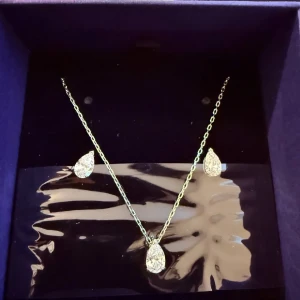 Swarovski smyckeset med droppform - Snyggt smyckeset från Swarovski med ett halsband och matchande örhängen. Både halsbandet och örhängena har droppformade, glittriga stenar i silverfärgade infattningar. Perfekt för dig som gillar stilrena och eleganta accessoarer. Vid köp av två eller fler får du dessutom välja en present 🎁❤️ (presenterna kan jag visa i DM eftersom de inte finns upplagda här).