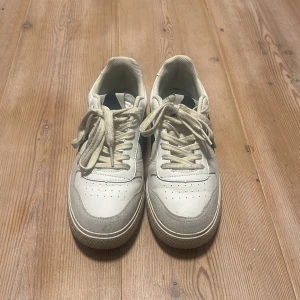 Vita sneakers från ARKK Copenhagen - Säljer mammas skor som är använda mellan 10 till 15 gånger. Snygga vita sneakers från ARKK Copenhagen med detaljer i mocka och skinn. Klassisk låg modell med snörning och platt sula. Perfekta för dig som gillar stilrena och fräscha skor med en sportig vibe. Köptes för 2 månader sen för typ 1100