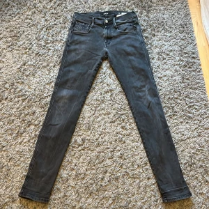Replay svarta jeans - Svarta skinny jeans från Replay med klassisk femficksdesign och detaljerad bakficka med Replay-logga. Jeansen har smal passform och är tillverkade i stretchigt jeanstyg för en bekväm känsla. Perfekta för dig som gillar en tajt siluett och stilren look. W30 L32. Äret som visas i bilden är syt igen och sitter väl.