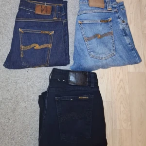 Nudie Jeans Bulk - Säljer tre par Nudie Jeans i olika färger: ett par mörkblå, ett par ljusblå och ett par svarta. Alla har klassisk femficksdesign, orangea sömmar och Nudie-logga på bakfickan. Perfekta jeans för dig som gillar stilrena och tidlösa byxor. Hör av er vid frågor🙌🏼 Priset är inte hugget i sten, går även att köpa styck🫱🏼‍🫲🏽
