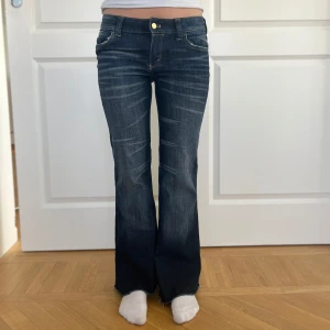 Cheap Monday flare jeans mörkblå - Mörkblå flare jeans från Cheap Monday med låg midja och slitna detaljer vid benslut. Klassisk femficksmodell med snygga slitningar framtill. Materialet är 71% bomull, 27% polyester och 2% elastan för en skön stretchig känsla. Byxorna är klippta nedtill så de passar perfekt för dig som är kring 160cm eller kortare💕💕💕