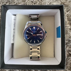 Curren Klocka - Curren Klocka, är i helt nytt skick förutom att baksidan har lossnat!