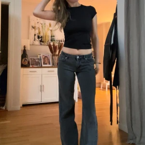 Svarta jeans från NA-KD - Säljer ett par svarta jeans från NA-KD med klassisk femficksdesign. Jeansen har normal midja och raka, vida ben. Tillverkade i mjukt denimtyg med dragkedja och knapp framtill. Perfekta för en avslappnad och trendig look. Lite slitage nere vid ena foton, men inget som stör❤️