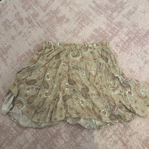 Beige paisleymönstrad kjol från Ecru - Supersöt kortkjol från Ecru i beige med paisleyinspirerat mönster i bruna och vita toner. Med built-in shorts under!