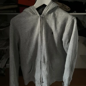 Grå hoodie från Polo Ralph Lauren XL - Säljer en grå hoodie från Polo Ralph Lauren i storlek XL. Tröjan har dragkedja, huva och två fickor framtill. Klassisk broderad logga på bröstet och tillverkad i mjuk bomullsmix. Perfekt för chill dagar eller när du vill ha en enkel och stilren look. På sista bilden är modellen 180cm väger 65kg