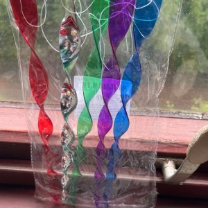 Vindspel - Bilden visar färgglada spiralformade plastdekorationer, troligen för utomhusbruk inga synliga märken eller modeller kan identifieras. Produkten verkar vara i nyskick och förpackad.