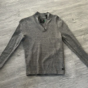 Grå stickad half zip-tröja Dockers - Snygg grå stickad tröja från Dockers med half zip-dragkedja och hög krage. Tröjan har lång ärm och en liten svart logolapp nertill. Perfekt för lager-på-lager och chill stil. Regular fit och mjukt material. Använd max 3 gånger skicket är suveränt!