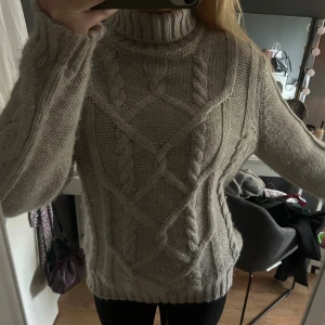 Beige stickad polotröja med flätmönster - Supermysig beige stickad polotröja med grovt flätmönster och ribbade muddar. Tröjan har en hög polokrage och lång ärm. Oversized fit som ger en chill och avslappnad vibe🍁🍁🍁🍁