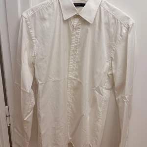 Vit skjorta från Selected Homme M - Klassisk vit skjorta från Selected Homme i storlek M. Skjortan har lång ärm, knappar framtill och en stilren krage. Tillverkad i bomull för en skön och luftig känsla. Perfekt för dig som gillar en clean och enkel look.