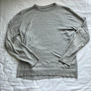 Grå och mörkgrå stickade tröjor - Två stilrena stickade tröjor i grå och mörkgrå färg. Båda har rund halsringning, ribbade muddar och lång ärm. Perfekta för lager-på-lager och passar till allt. Materialet är mjukt och tunt, vilket gör dem sköna att bära under höst och vinter.