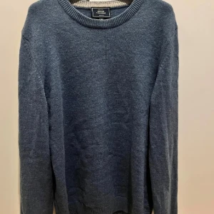 Blå Kashmir Tröja - Mysig blå stickad kashmir merino blend tröja med rund halsringning och ribbade muddar. Perfekt för lager-på-lager och chill dagar. Enkel och stilren design som funkar till det mesta. Har ett litet hål i armen men inget som syns vid användning!