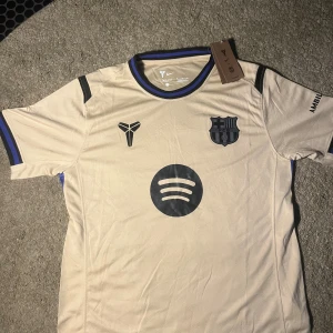 Beige FC Barcelona Nike fotbollströja M - Fotbollströja Nike Dri-FIT Barcelona ⚽️ 249kr Nike Dri-FIT Barcelona fotbollströja i beige med svarta och blå detaljer. Helt ny med etiketter.  ⭐️ Skick: 10/10 🎨 Färg: Beige 📦 Snabb Frakt
