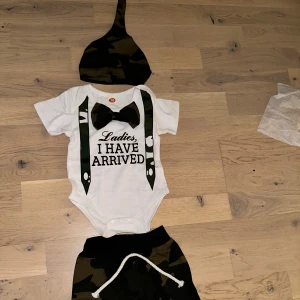 Barnset med body, mössa och byxor – "Ladies, I have arrived" - Ett charmigt och bekvämt set för de allra minsta! Setet består av en mjuk body med trycket "Ladies, I have arrived", matchande byxor och en söt liten mössa. Perfekt som present till en nyfödd eller till barnets första garderob. Tillverkat i mjuk och skön bomull som är snäll mot barnets hud Praktiska tryckknappar i grenen för enkel på- och avklädning Stretchig resår i byxlinningen för extra komfort Mössa som håller det lilla huvudet varmt Ett gulligt och roligt set som garanterat väcker leenden!