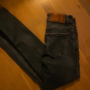 Mörkblåa Tiger of Sweden jeans  - Snygga mörkblå jeansbyxor från Tiger of Sweden med klassisk femficksdesign och bruna kontrastsömmar. Byxorna har en skinnpatch med logga bak i midjan och raka ben. Perfekta för dig som gillar stilrena och tidlösa jeans.                               Sprillans nya! | Dm vid några frågor 📩