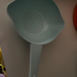 Ljusblått plastdurkslag med handtag - Ett ljusblått durkslag i plast med långt handtag och rundad skålform. Perfekt för att sila pasta, ris eller grönsaker. Durkslaget har små hål i botten och ett hål i handtaget för enkel upphängning i köket.