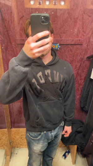 Svart hoodie med stjärna och tryck - Säljer en svart hoodie med stor stjärna och text på bröstet. Tröjan har huva, känguruficka och ribbade muddar. Perfekt för dig som gillar en avslappnad och cool stil. Storlek L men sitter perfekt till M