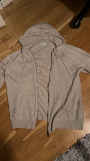 Kashmir hoodie från Davida Cashmere  - Mysig beige Kashmir hoodie från Davida cashmere i storlek XL. Tröjan har huva med snörning, dragkedja framtill och två fickor. Tillverkad i mjukt material och har långa ärmar. Perfekt för chill dagar eller när du vill ha något bekvämt. Tröjan är ungefär helt ny inga defekter finns på varan kom med frågor och funderingar😚