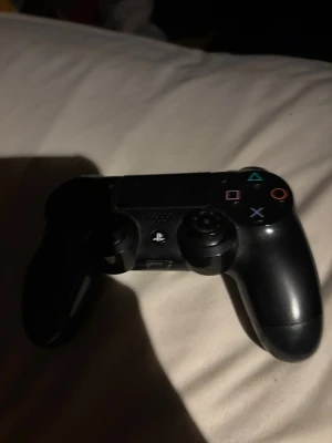PlayStation DualShock 4 Wireless Controller - Snygg svart PlayStation DualShock 4 trådlös handkontroll. Alla knappar och styrspakar syns tydligt, med mindre tecken på normalt slitage. Perfekt för PlayStation 4-spelare som vill ha en extra eller ersättningskontroll.