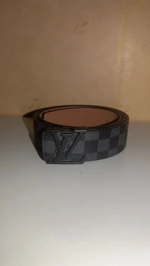 Svart randigt bälte 110 - Ett svart bälte med ett svart spänne helt nyt aldrig använt perfekt för att ge en lyxig touch på din outfit 