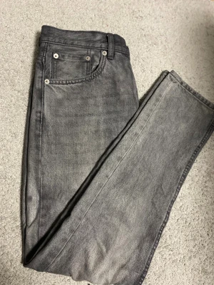 Grå jeans från 157 New Classic - Snygga grå jeans från 157 New Classic med klassisk femficksdesign och raka ben. Jeansen har en tvättad look och är tillverkade i slitstarkt denimtyg. Perfekta för dig som gillar en stilren och enkel vibe.