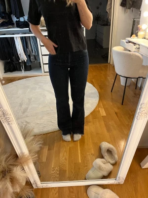 Mörkblå bootcut jeans - Snygga mörkblå jeans med bootcut passform och klassisk femficksdesign. Jeansen har medel hög midja och är tillverkade i ett stretchigt denimtyg som sitter skönt och formar benen. Jeansen är avklippta lägst ner och passar mig som är 168cm