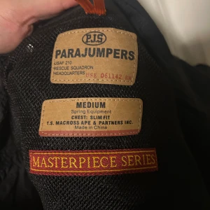 Svart pufferjacka från Parajumpers M - parajampers rescue squadron - Svart pufferjacka från Parajumpers i storlek medium. Jackan har broderad patch på ärmen, quiltad design och klassisk pufferlook. Slim fit-modell med snygga detaljer och sportig känsla. Perfekt för dig som vill ha en stilren och varm jacka med streetvibe.