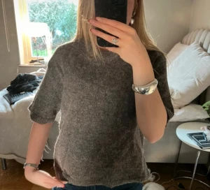 Brun stickad tröja från Gina Tricot - Mysig brun stickad tröja från Gina Tricot i storlek XS. Tröjan har korta ärmar, rund hals och är gjord i ett fluffigt material som känns skönt mot huden. Perfekt att styla med jeans eller kjol för en chill look.