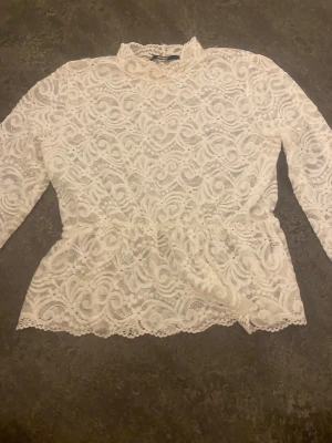 Vit spetsblus från Bik Bok - Säljer en vit blus från Bik Bok i storlek L, helt i spets med vackert broderat mönster och hög hals. Blusen har långa ärmar och fina detaljer längs kanterna. Perfekt för dig som gillar romantisk och feminin stil.