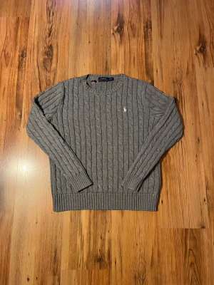 Grå kabelstickad tröja Polo Ralph Lauren - Grå kabelstickad Ralph Lauren tröja 🏇🏽 Size XS/160-165 (Vet inte varför de står M)  Mått ⤵️  📏 Längd (Axel till mudd) - 55 cm  Bröstbredd - 46 cm  Ärmlängd - 54 cm   - 9/10 skick, inga defekter, ren och fräsch - Finns en tapelapp vid nacken men den täcker inga skador   Hör av er om ni har frågor 🤩