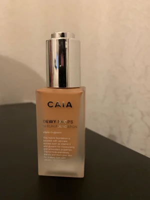 CAIA Dewy Drops Serum Foundation 30N - Foundation från CAIA i nyansen 30N. Kommer i en snygg frostad glasflaska med silvrig pump. Ger en dewy finish och innehåller vitamin E och glycerin för extra fukt. Perfekt för dig som vill ha en naturlig glow och lätt täckning. Där jag håller fingret är så mycket som finns kvar :) 
