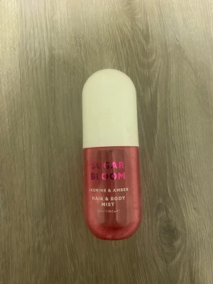 Sugar Bloom Hair & Body Mist - Fräsch mist för hår och kropp med jasmin och amber. Volym: 100 ml. Ingredienser: Alcohol Denat., Aqua, Fragrance (Parfum), PEG-40 Hydrogenated Castor Oil, Propylene Glycol, Limonene. Perfekt för dig som vill ha en enkel och snabb uppfräschning. Luktar som Sol De Janeiro 