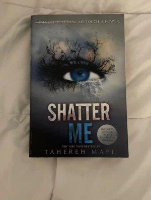 Shatter Me - En spännande New York Times-bestseller med ett mystiskt omslag som visar ett blått öga och dramatiska trädgrenar. Perfekt för dig som gillar intensiva berättelser och starka karaktärer. Boken lockar med temat om kraft och makt, och passar unga vuxna som söker något utöver det vanliga.