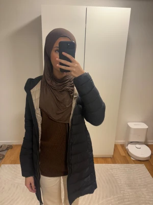 Svart lång dunjacka Parajumpers - Säljer en svart lång dunjacka från Parajumpers med huva och quiltad design. Jackan har dragkedja framtill och en patch med logga på ärmen. Insidan är ljusgrå och jackan har en normal passform som är perfekt för kalla dagar. Den är i ett väldigt bra skick.