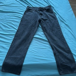 Svarta Jack & Jones jeans  - Säljer ett par svarta jeans från Jack & Jones, modell Relaxed Chris. Jeansen har en avslappnad passform med raka ben och klassisk femficksdesign. Tillverkade i denim och läderpatch bak i midjan. Perfekta för en chill och stilren look. Storlek 31/32