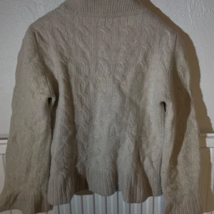 Beige kabelstickad tröja Marville Road - Säljer en beige kabelstickad tröja från Marville Road i storlek 42. Tröjan har långärmade ribbade muddar och en rundad hals med bred ribbad kant. Materialet är mjukt och värmande, perfekt för kyliga dagar. Snyggt flätmönster över hela tröjan.