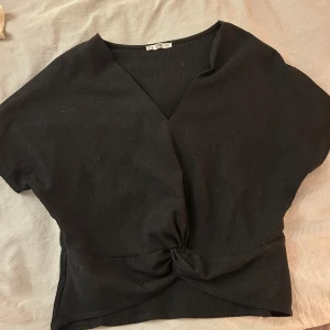 Svart omlottopp med knut från Zara - Svart omlottopp från Zara med v-ringning och knutdetalj framtill🖤