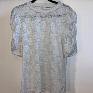 Vit spetsblus från Kappahl - Säljer en vit blus från Kappahl i storlek M. Blusen är helt i spets med blommigt mönster, har puffiga korta ärmar och rund halsringning. Knappt använd 