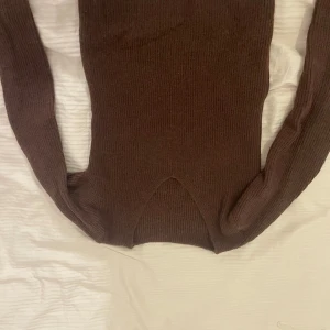 Brun stickad tröja v ringad - Mysig brun stickad tröja med lång ärm och en snygg slitsdetalj framtill. Perfekt för lager-på-lager och passar till både jeans och kjol. Ribbstickad struktur ger en trendig look.