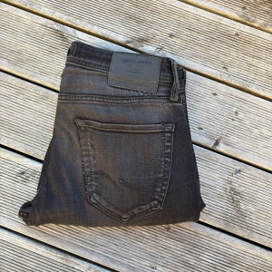 Svarta slim jeans Jack & Jones - Säljer ett par svarta slim fit jeans från Jack & Jones, modell Glenn. Jeansen har klassisk femficksdesign, dragkedjegylf och en snygg sliten look med en reva på ena benet. Materialet är stretchigt denim för skön passform. 31/32. Kom gärna med offer/frågor🙏