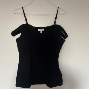 Svart linnetopp från H&M Edition - Snygg svart linnetopp från H&M Edition med smala justerbara axelband och figurnära passform. Toppen har en enkel och stilren design som passar perfekt till jeans eller kjol. Materialet känns mjukt och följsamt mot kroppen.