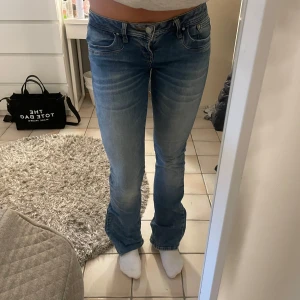 Blå bootcut jeans med låg midja - Säljer ett par blå jeans med snygg tvätt och lätt slitning. Modellen har låg midja och bootcut-ben som ger en schysst siluett. Klassisk femficksdesign och bekvämt jeansmaterial. Perfekta för dig som gillar en avslappnad men trendig look.
