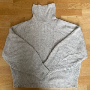 Beige polotröja i ullmix från H&M - Mysig beige polotröja från H&M i storlek M. Tröjan är stickad med ribbade muddar och hög polokrage, perfekt för kyliga dagar. 