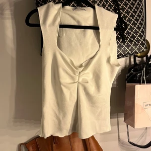 Vit topp från Zara - Säljer en stilren vit ärmlös topp från Zara med snygg rynkdetalj framtill. Jättetrendig och slutsåld topp från zara!!😍 storlek L men passar M 
