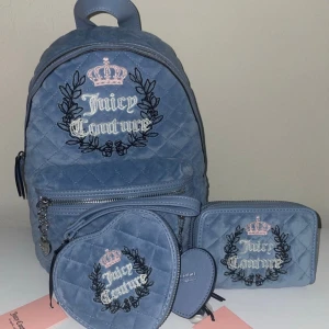 Juicy Couture blå quiltad ryggsäck set - Superfint set från Juicy Couture med quiltad blå ryggsäck, matchande plånbok och hjärtformad liten väska. Alla delar har broderad krona och logga i vitt och rosa, samt svarta detaljer. Väskorna är i mjuk sammet och har dragkedjor med snygga detaljer.