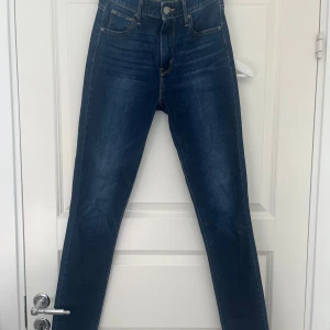 Levi's 721 High Rise Skinny Jeans - Mörkblå Levi's 721 High Rise Skinny jeans med klassisk femficksdesign och snygga kontrastsömmar. Hög midja och tight passform hela vägen ner. Tillverkade i stretchig denim för en bekväm känsla och perfekt passform. Passar för lång är själv 178