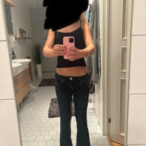 Mörkblå bootcut jeans från True Religion - Säljer ett par mörkblå Joey jeans från True religion som är bootcut och låg midja. Jeansen har snygga sömmar, dekorativa bakfickor med lock och knapp bak. Perfekta för dig som gillar snygga och sköna jeans!