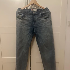 Levi's Loose Taper jeans blå - Säljer ett par Levi's Loose Taper jeans i klassisk ljusblå tvätt. Jeansen har en avslappnad passform med avsmalnande ben och fem fickor. Perfekta för dig som gillar en loose men ändå snygg siluett. Levi's-logga på bakfickan och etikett i midjan.