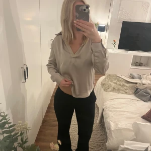 Beige sidenblus med v-ringning - Säljer en stilren beige blus i siden med v-ringning och långa ärmar. Blusen har en avslappnad passform och snygga manschetter vid ärmsluten. Perfekt för dig som gillar en enkel men elegant look.