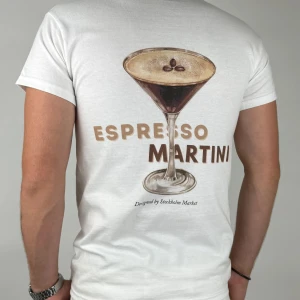 Espresso Martin - Låt sommaren leva vidare i varje steg med Espresso Martini – en avslappnad t-shirt inspirerad av friska jordgubbar, iskalla cocktails och lata dagar i solen.  Material: 100% mjuk och slitstark bomull Passform: Unisex, normal i storleken Färg: Klassisk vit med färgstarkt motiv Detalj: Tryck på ryggen, liten märkning nedtill